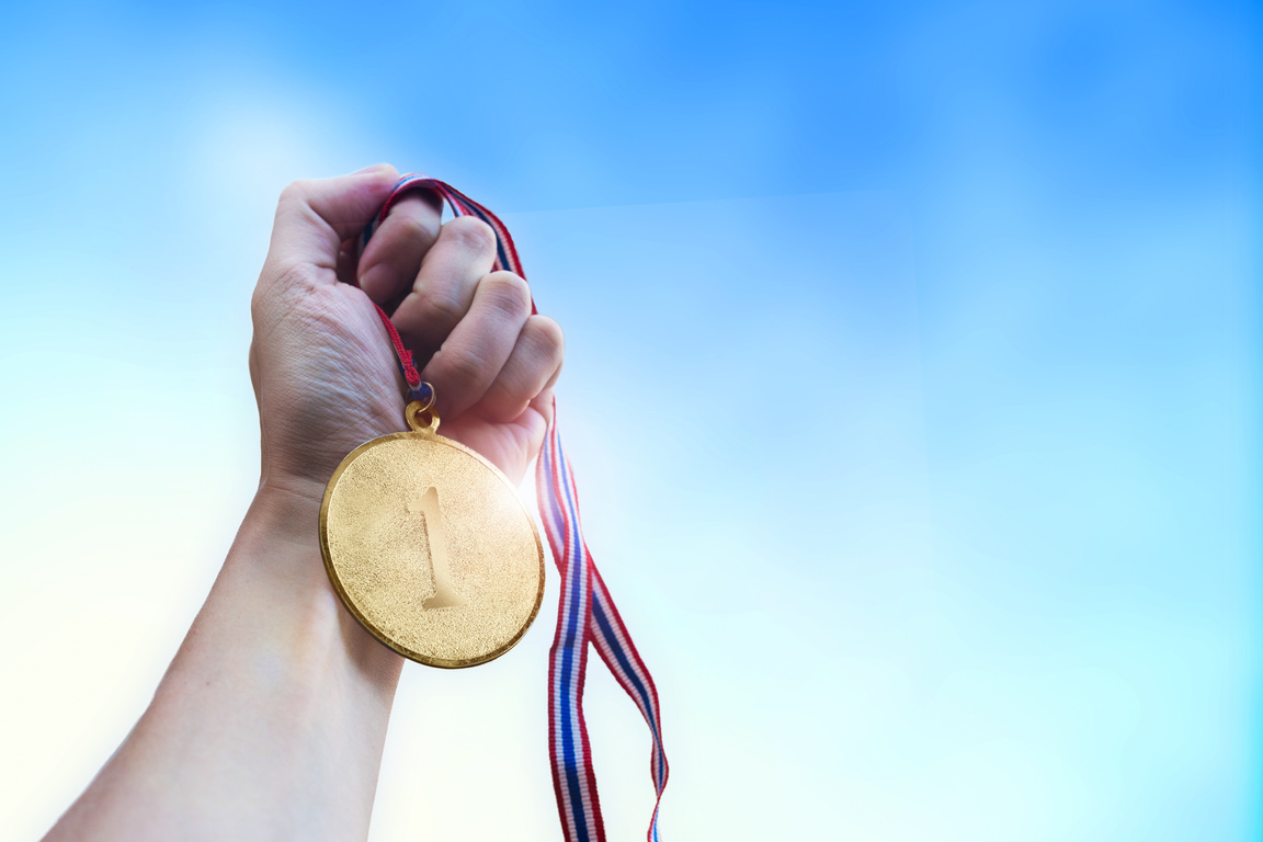 Athletic man hand holding golden coin medal.
